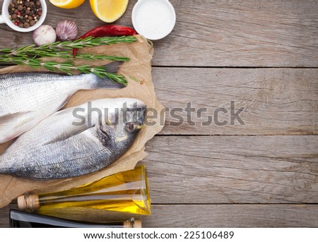 Fresh dorado fish cooking with spices and condiments on wooden table with copy space