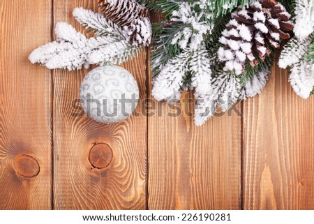 Christmas fir tree with snow and bauble on rustic wooden board with copy space