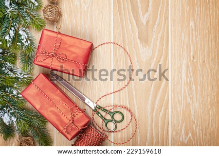Christmas presents wrapping and snow fir tree over wooden table background with copy space