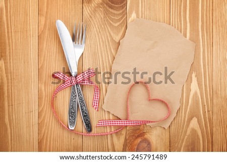 Blank paper for recipe or note and silverware on wooden table background