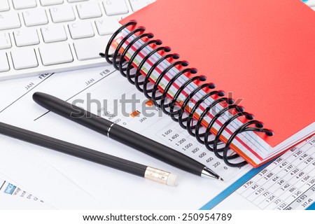 Office desk with reports, blank notepad and supplies. Closeup