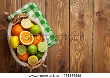 Citrus fruits in basket. Oranges, limes and lemons. Top view over wooden table background with copy space