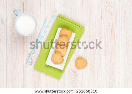 Cup of milk and heart shaped cookies on white wooden table with copy space