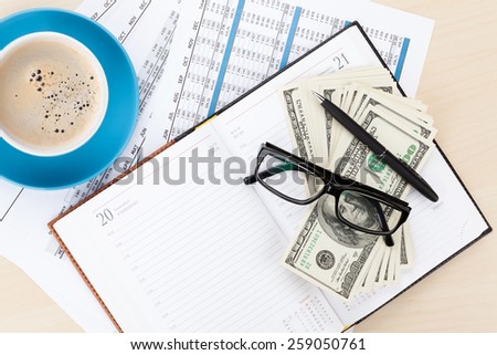 Office desk with reports, blank notepad and money cash. View from above with copy space
