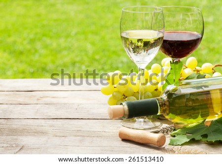White and red wine glasses, wine bottle and white grape on wood table with copy space