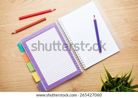 Office table with flower, blank notepad and colorful pencils. View from above with copy space