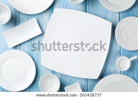 Empty plates and bowls on blue wooden background. Top view with copy space