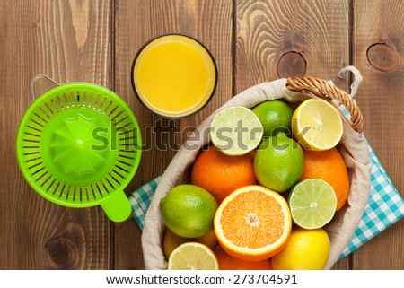 Citrus fruits and glass of juice. Oranges, limes and lemons. Top view over wood table background