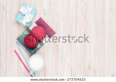 Colorful macarons, cup of milk and gift box on white wooden table with copy space