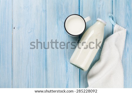 Milk cup and bottle on wooden table. Top view with copy space