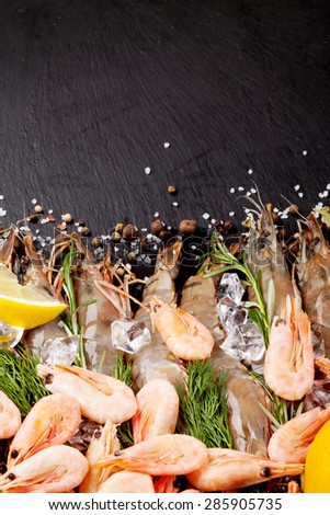 Fresh prawns with spices on black stone background. Top view with copy space