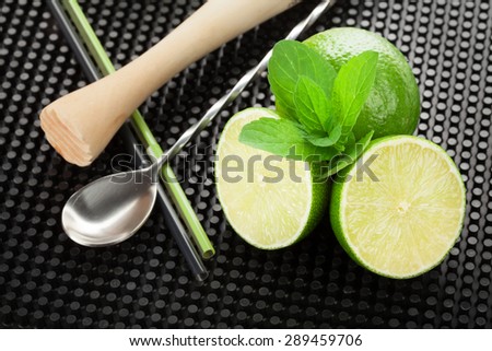 Mojito cocktail ingredients and utensils on black rubber mat