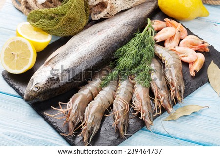 Fresh raw sea food with spices on stone plate over wooden table background. Top view