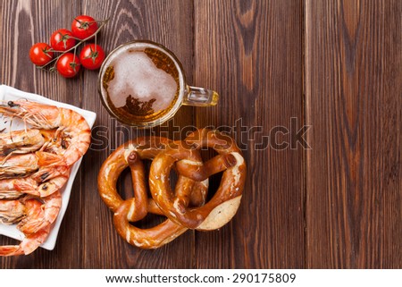 Pretzel, beer mug and grilled shrimps on wooden table. Top view with copy space