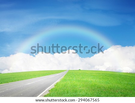 Summer landscape with endless asphalt road through the green field and blue sky with clouds and rainbow