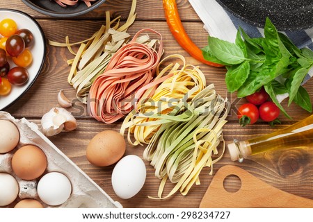 Pasta cooking ingredients and utensils on wooden table. Top view