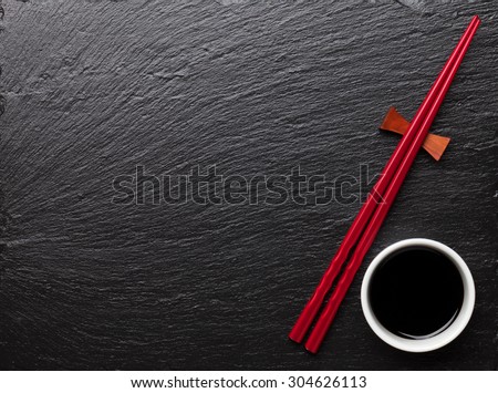 Japanese sushi chopsticks and soy sauce bowl on black stone background. Top view with copy space