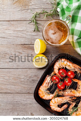 Grilled shrimps on frying pan and beer. Top view with copy space