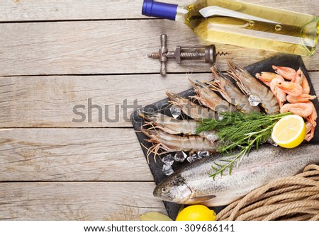Fresh raw sea food with spices and white wine on wooden table background. Top view with copy space