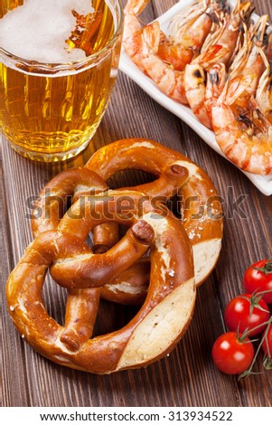 Pretzel, beer mug and grilled shrimps on wooden table