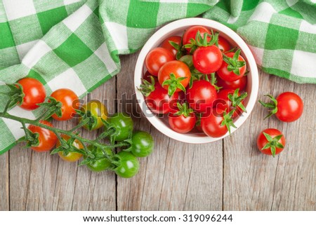 Cherry tomatoes bowl on wooden table. Top view