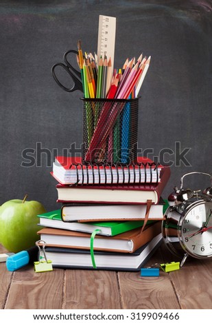 School and office supplies on classroom table in front of blackboard