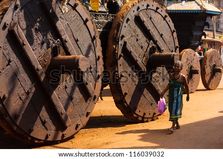 GOKARNA, INDIA - MARCH 3: Unidentified Indian woman walks by enormous wooden wheels of the big ratha chariot, a vehicle used in Gokarna for hindu festivals, on March 3, 2009 in Gokarna, India