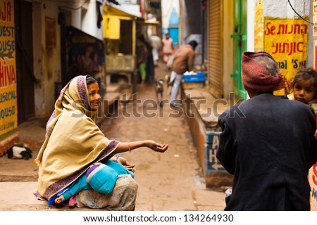 VARANASI, INDIA - JANUARY 31, 2008: An unidentified poor woman with baby begs for money from a passerby in the holy city of Varanasi, India on January 31, 2008. Poverty is a major issue in India