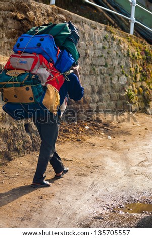 DARJEELING, INDIA - DECEMBER 26: An unidentified Indian porter carries a heavy load on December 26, 2007 in Darjeeling, India. Unskilled laborers are left behind in India\'s economic boom