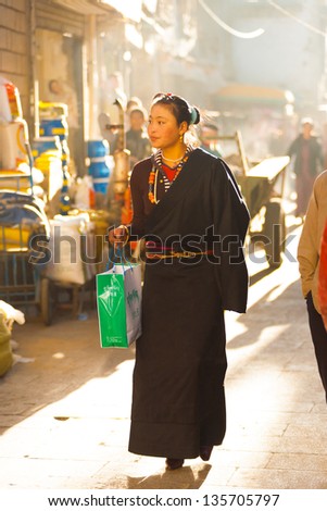 LHASA, CHINA - OCTOBER 17: A unidentified modern attractive young Tibetan woman walks the traditional Barkhor circuit, a famous tourist destination in Tibet on October 17, 2007 in Lhasa, China