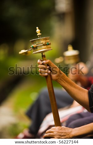 A brass prayer wheel (mani) is spun clockwise while a mantra is recited.