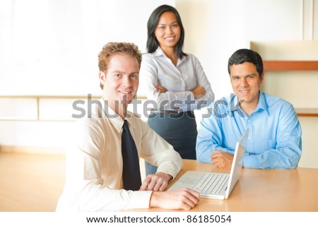 A caucasian man leads a business meeting with an Asian female and latino male