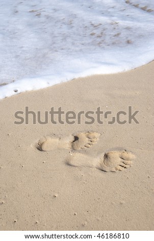 Footprints in the sand about to be washed away on the sea shore