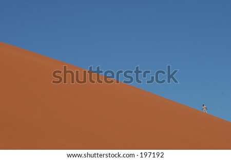 Man climbing a sand dune, Namibia, Africa