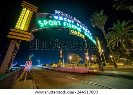 SANTA MONICA - JAN 14, 2015: Famous Santa Monica Sign - Entrance to Santa Monica Pier on Ocean Avenue in LA California at Night with People. Santa Monica is a beachfront city in LA California.
