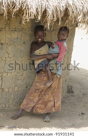 LIRA, UGANDA - JUNE 9: An unidentified girl holds her baby brother under thatched roof of their hut in Lira, Uganda on June 9, 2007. UNHCR estimates there to be over 136,000 refugees in Uganda.