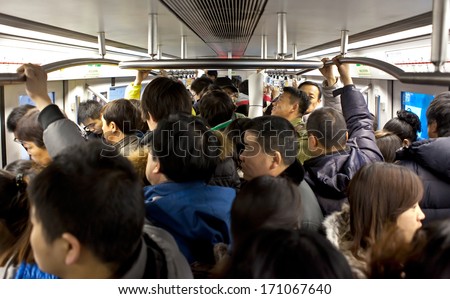 BEIJING, CHINA - JAN. 12, 2014: Crowded subway train during rush-hour. Any subway trip, costs only 2 yuan (33 US cents); Beijing government\'s  plans to reform the current low-cost subway ticket system