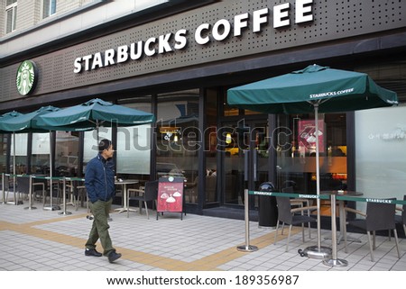BEIJING, CHINA - NOV 10, 2013: A man is seen walking nearby a Starbucks coffee store. Starbucks is the largest coffeehouse company in the world, with 20,891 stores in 64 countries