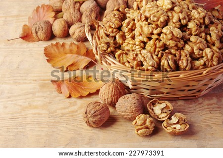 Walnut kernels in basket and whole walnuts on rustic old wood