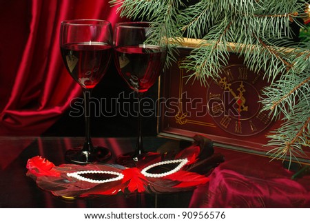Two glasses of red wine, clock and mask