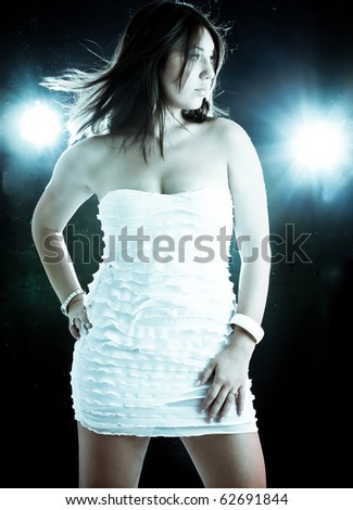 Toned image of a Beautiful girl in a white dress and dramatic disco-like lightning