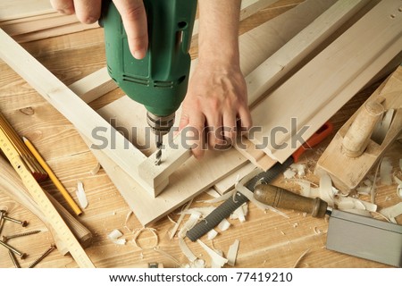 Wooden workshop table with tools. Man\'s arms drill plank.
