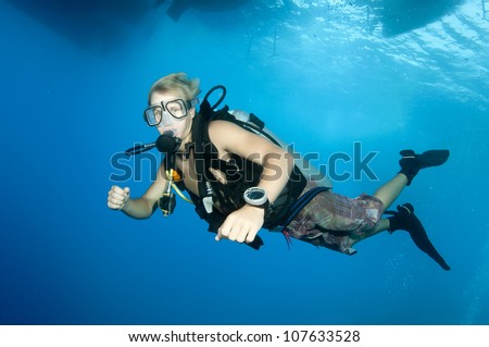 young scuba diver swims under dive boat