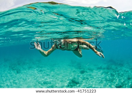 Man snorkeling underwater with surface reflection