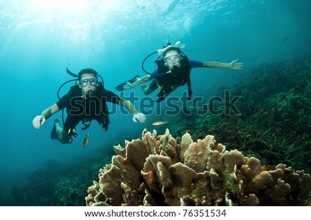 Young couple scuba dive together on a coral reef