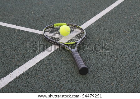 Tennis racket (racquet) and ball on white T line of a tennis court