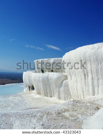 Winter-like landskape with white travertine instead of snow, limestone pool instead of ice and improbably blue sky in the background