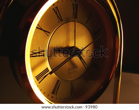 Old style mantel clock with roman numerals in ambient light.