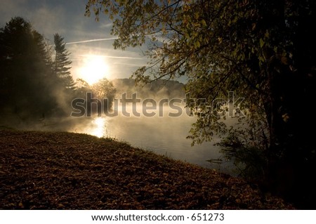 A surreal looking morning in the fall with the mist rising from the lake as the sun rises.