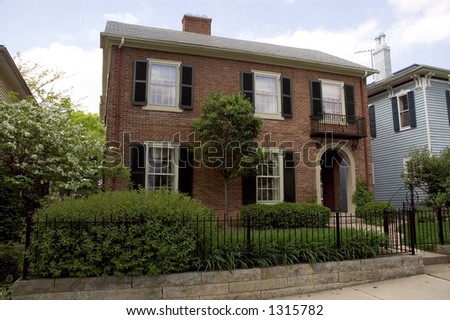 A beautiful elegant red brick home.Features some nice wrought iron details with a fence and gate and also a balcony.